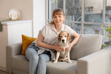 Evdeki kanepede oturan sevimli av köpekli genç kadın.