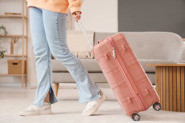 Bavullu bir kadın turist evde yürüyor.