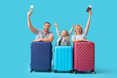 Kızlarıyla mutlu bir çift, pasaportları ve bavulları mavi arka planda.