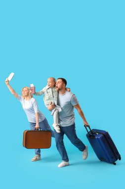 Aile, mavi arka planda bavullar ve pasaportlarla çalışıyor.