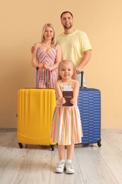 Bej duvarın yanında ailesi ve bavulları olan küçük bir kız çocuğu.
