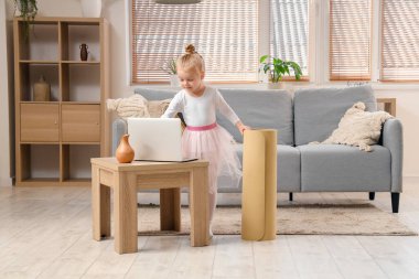 Cute little ballerina training with laptop at home