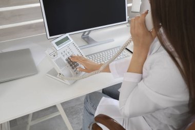 Klinikte telefonla konuşan kadın resepsiyonist, yakın plan.