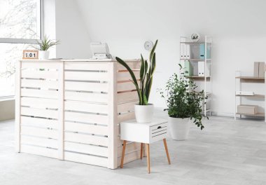 Resepsiyon masası ve bitkileri olan bir klinik.