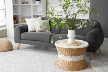 Oturma odasındaki masanın üzerinde çiçek açan bir vazo.