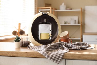 Mutfaktaki masada kahve fincanı ve bir kavanoz fasulye olan modern kahve makinesi.