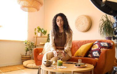 Evinde kristal küre kayıt videosu olan genç bir Afro-Amerikan cadı.