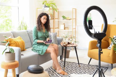 Genç Afro-Amerikan cadı ve tarot kartları evdeki kanepede video kaydediyor.