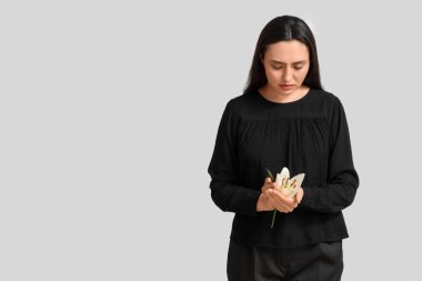 Beyaz arka planda zambak çiçeği olan genç bir kadın.