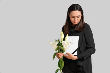 Nilüfer çiçeği buketi ve beyaz arka planda fotoğraf çerçevesi olan genç bir kadın.