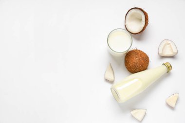 Beyaz zemin üzerinde hindistan cevizi sütü olan şişe ve bardak.