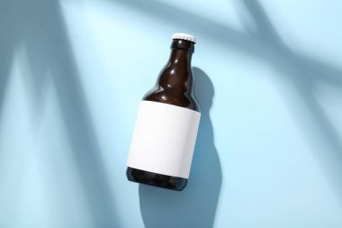 Açık mavi arkaplanda bir şişe soğuk bira.