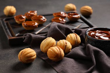 Lezzetli ceviz şekilli kurabiyeler ve siyah grunge masasında kaynamış süt.