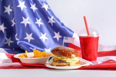 Nachos, kola ve beyaz arka planda Amerikan bayrakları olan lezzetli bir burger. Amerikan Bağımsızlık Günü kutlamaları