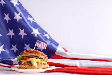 Beyaz arka planda ABD bayrakları olan lezzetli bir burger. Amerikan Bağımsızlık Günü kutlamaları