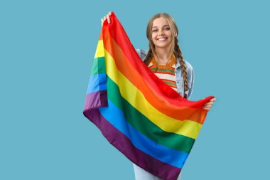 Beautiful young woman with LGBT flag on blue background