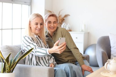 Mutlu olgun kadınlar evde selfie çekiyorlar.