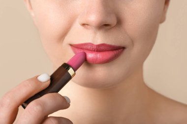 Bej arka planda pembe ruj süren kadın, yakın plan.
