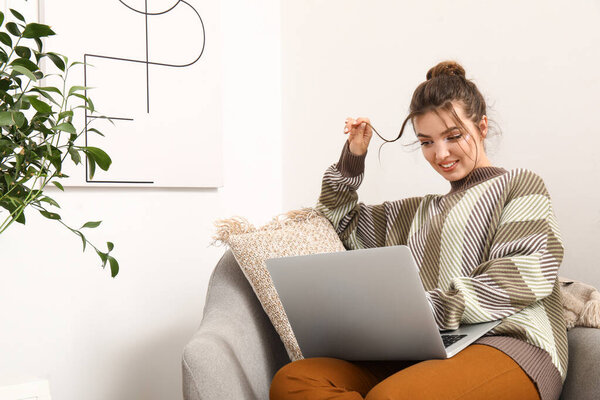 Женщина-фрилансер работает с ноутбуком в кресле дома