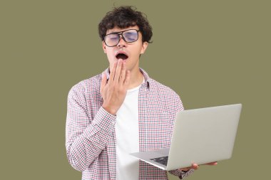 Yeşil arka planda dizüstü bilgisayarı olan uykulu erkek programcı