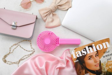 Portatif elektrikli vantilatör, dizüstü bilgisayar ve beyaz grunge arka planda şık kadın aksesuarları ile kompozisyon