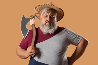 Hasır şapkalı olgun oduncunun bej arka planda baltası olan portresi