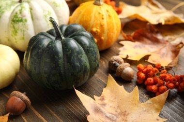 Kahverengi ahşap arka planda balkabağı ve sonbahar yapraklarıyla kompozisyon