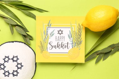 Dört tür (lulav, hadas, arava, etrog), kippah ve yeşil arkaplanda Mutlu SUKOT yazılı tebrik kartı