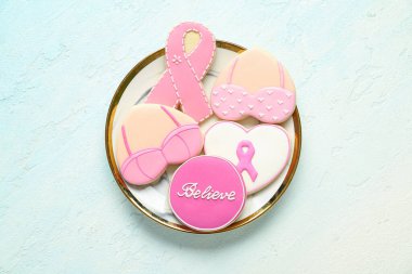 Mavi grunge arka planda pembe kurabiyeli tabak. Göğüs kanseri farkındalığı konsepti