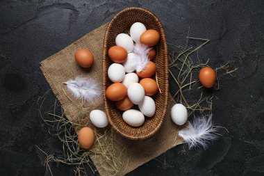 Hasır kase, çiğ tavuk yumurtası ve siyah arka planda saman.