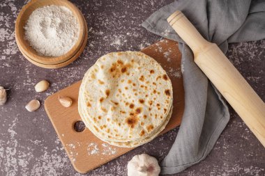 Gri arka planda tahtadan yapılmış lezzetli pide ekmeği ve unu var.