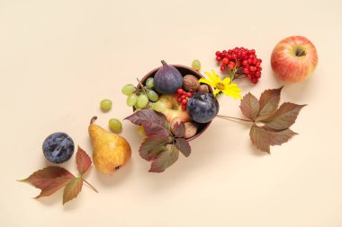 Bej arka planda farklı taze meyvelerle dolu bir kase.