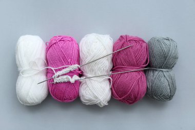 Gri arka planda iplik topları ve örgü iğneleri