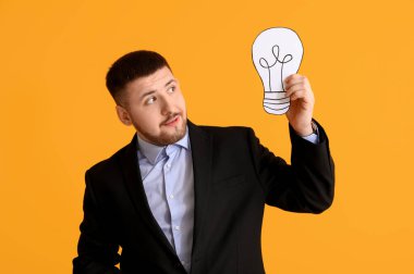 Sarı arka planda ampulü çizilmiş genç bir iş adamı. İş fikri kavramı