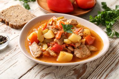 Lezzetli biftek güveci ve beyaz ahşap arka planda maydanoz.