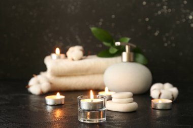 Karanlık arka planda mum ve spa malzemeleri yakmak