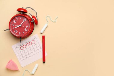 Regl takvimi, alarm saati ve kadın hijyen ürünleri ile renk arkaplanı bileşimi