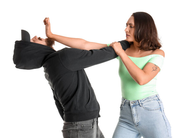 Young woman defending herself against robber on white background