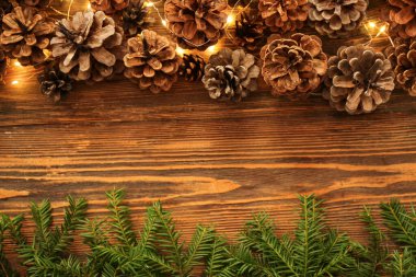 Noel ışıkları ve ahşap arka planda köknar dalları olan çam kozalakları