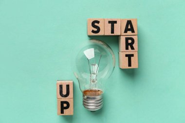 Sözcükler STARTUP ve yeşil arkaplanda ampul