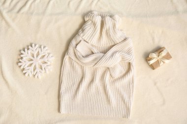 Şık, sıcak süveter, Noel hediyesi ve açık kumaş arka planda dekor.