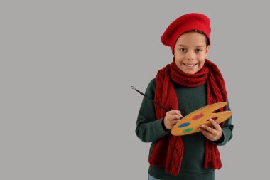 Gri arka planda boya paleti olan, kalın giysili yakışıklı Afro-Amerikalı çocuk.