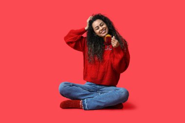 Kırmızı arka planda cam bardak sıcak şarap ile mutlu genç Afro-Amerikalı kadın