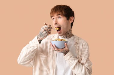 Bej arka planda mısır gevreği yiyen adam.