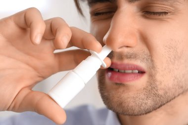 Hasta işadamı ofiste burun damlası kullanıyor, yakın plan.