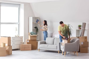 Mutlu genç çift taşınma gününde eşyalarını odaya topluyor.