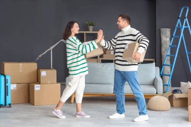 Kutuları olan mutlu genç çift taşınma gününde odada beşlik çakıyor.