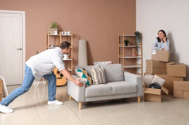 Taşındığı gün kocasıyla birlikte odada kanepe taşıyan mutlu genç bir kadın.