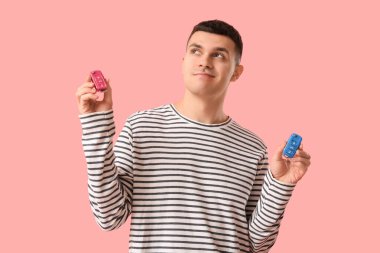 Pembe arka planda araba anahtarı olan genç bir adam.