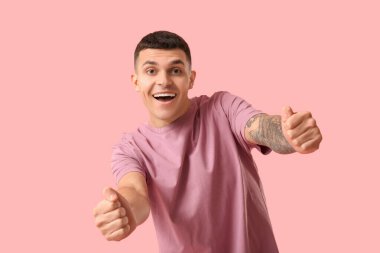 Pembe arka planda hayali direksiyonu olan genç bir adam.